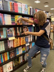 A woman in blue shirt and jeans looking at books.